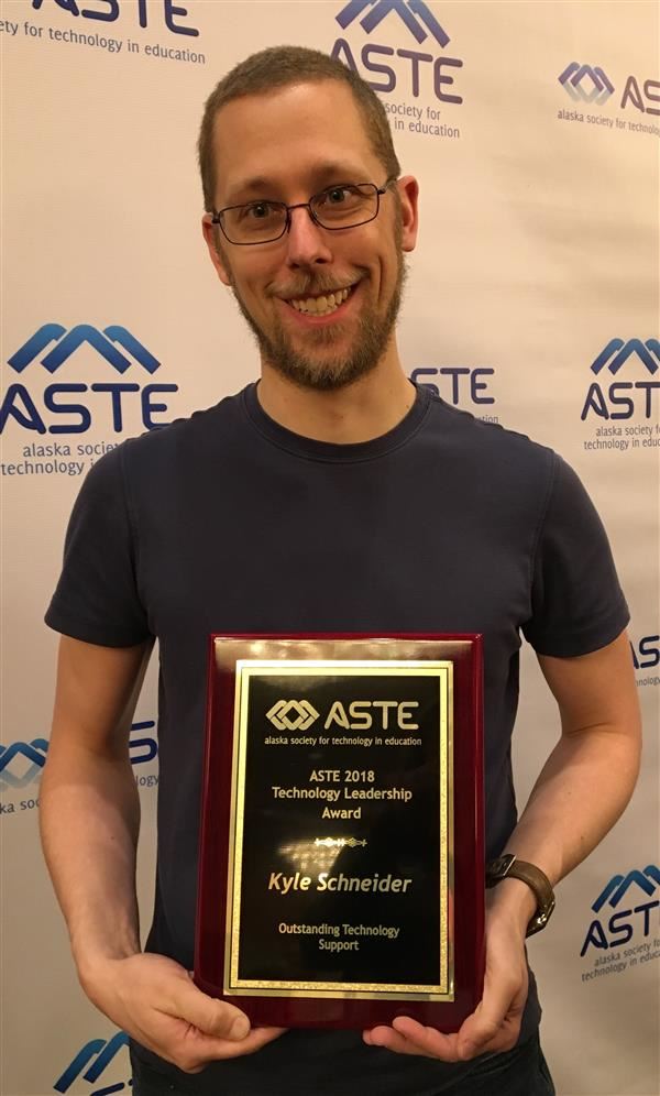  Student Support Specialist Kyle Schneider holds his award.
