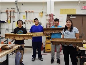 Students displaying coat racks made in woodworking class.  