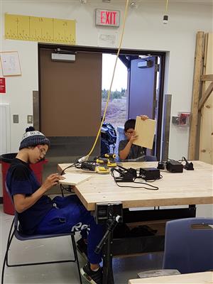 Students sanding boards for woodburning  