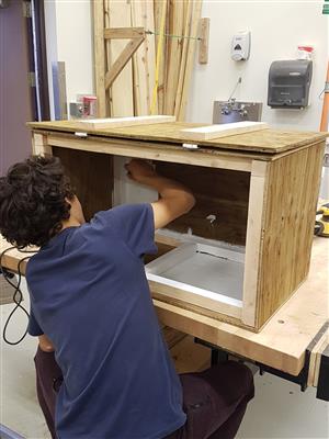 Student painting the chest he built  