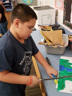 Student cutting the groove on his ice fishing pole  