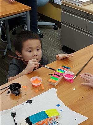 1st graders painting his pinewood derby car  