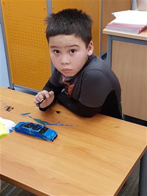 Boy painting pinewood derby car  
