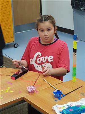 Elementary student painting her pinewood derby car  