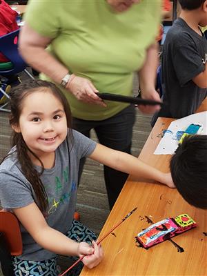 Student painting her pinewood derby car  