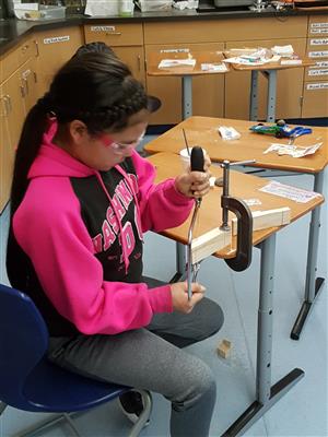 Student using coping saw to shape pinewood derby car 