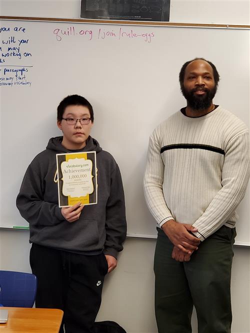 student with certificate standing with teacher 