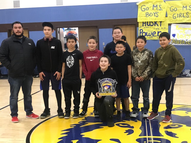 Koliganek Middle School boys Basketball team poses with their coach and trophy.